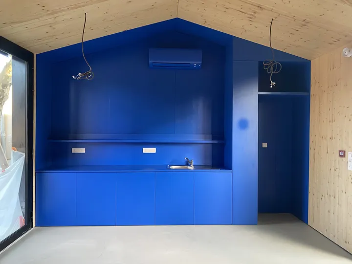Alcôve laquée bleu électrique en forme de maison, dans un volume en panneaux de bois massif