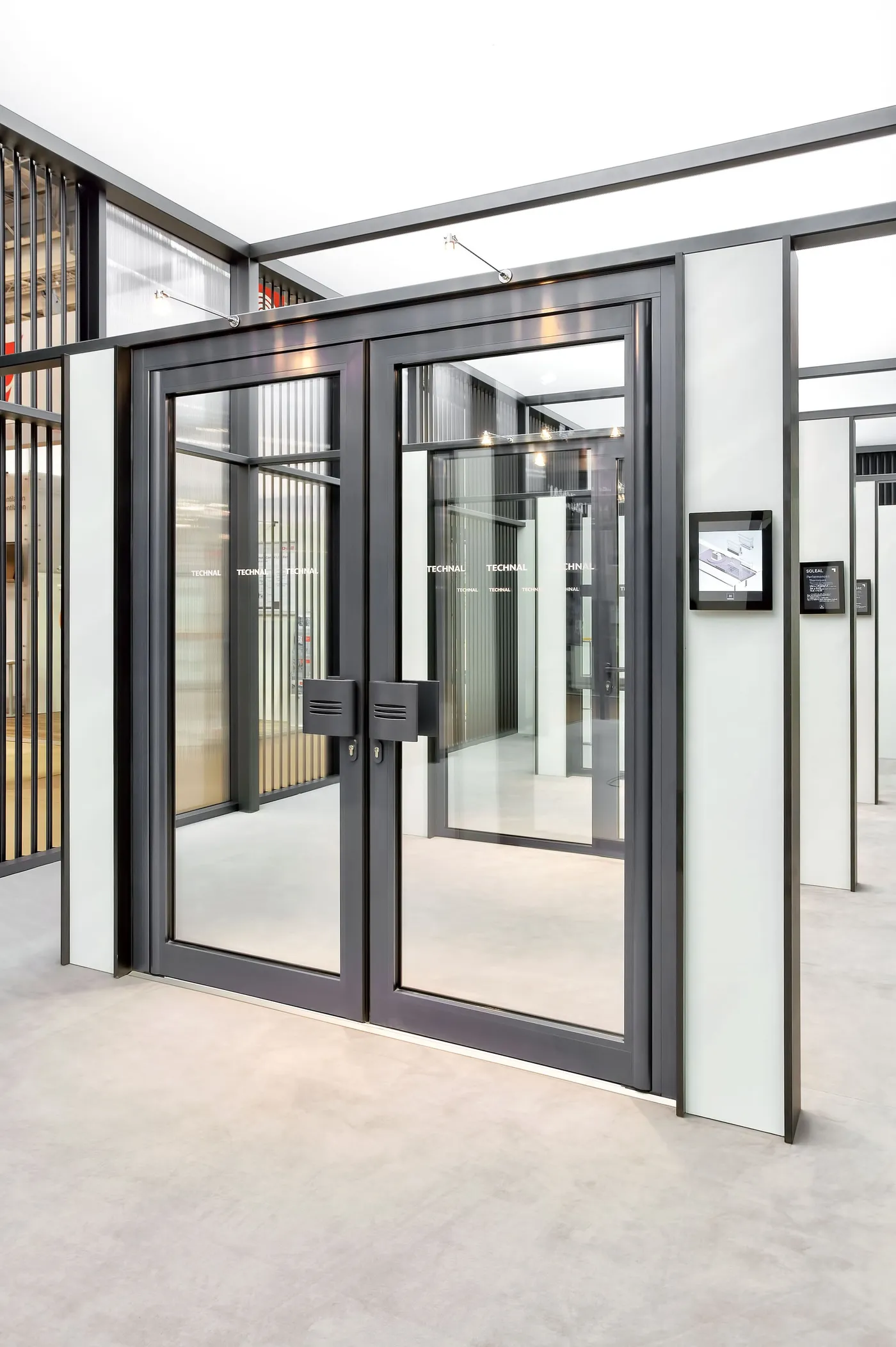 Double porte vitrée aluminium à poignées tubulaires dans un couloir lumineux