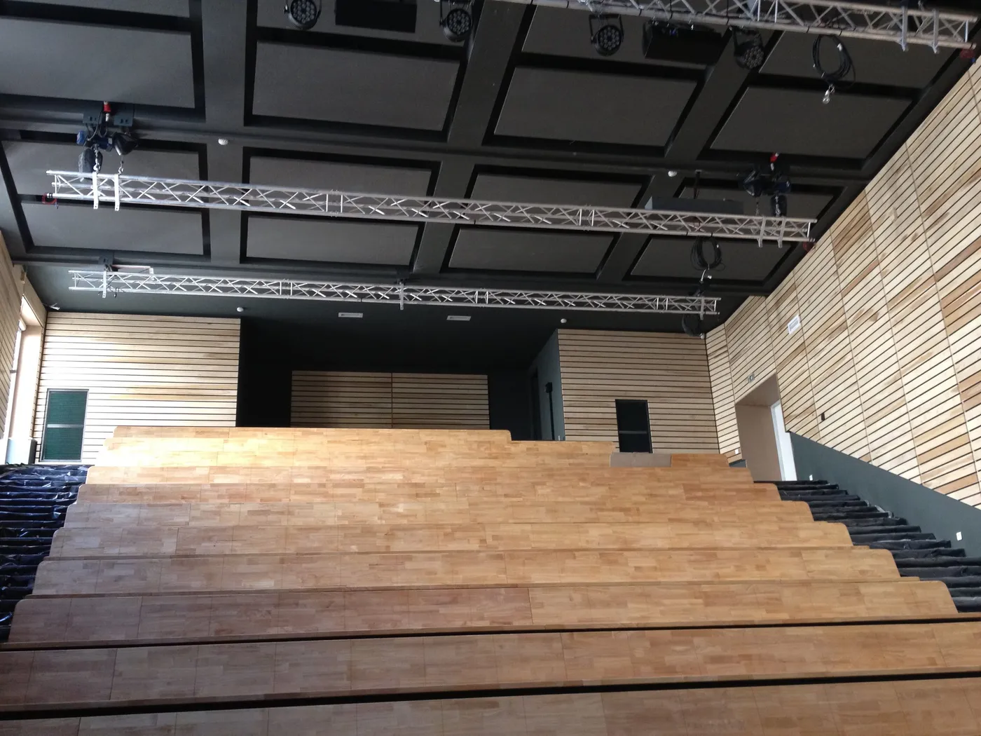Auditorium aux murs habillés de lames de bois clair, gradins en bois