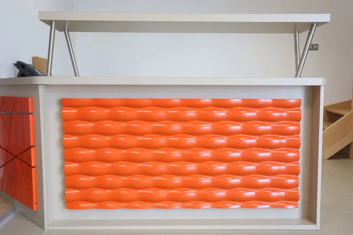 Banque d'accueil à façade orange ondulée en relief