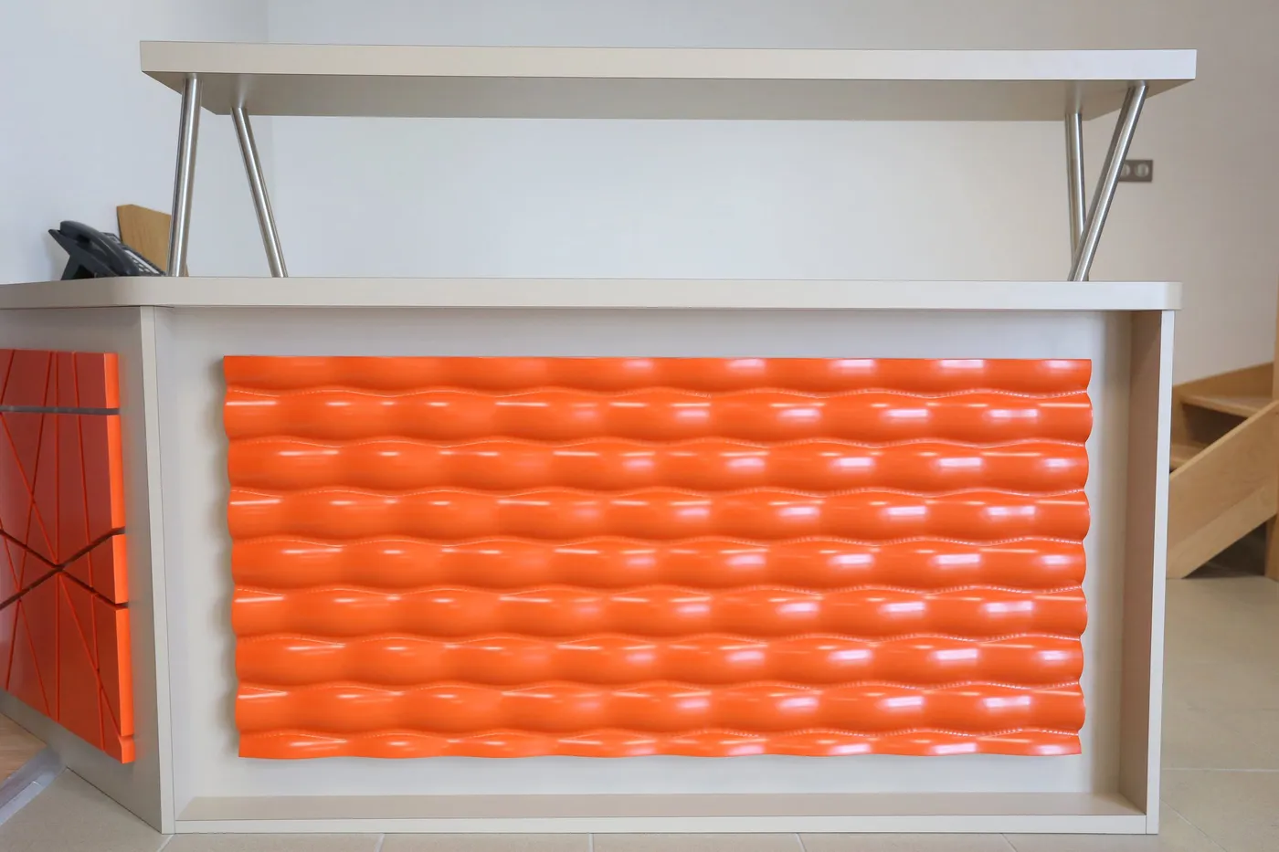 Banque d'accueil à façade orange ondulée en relief