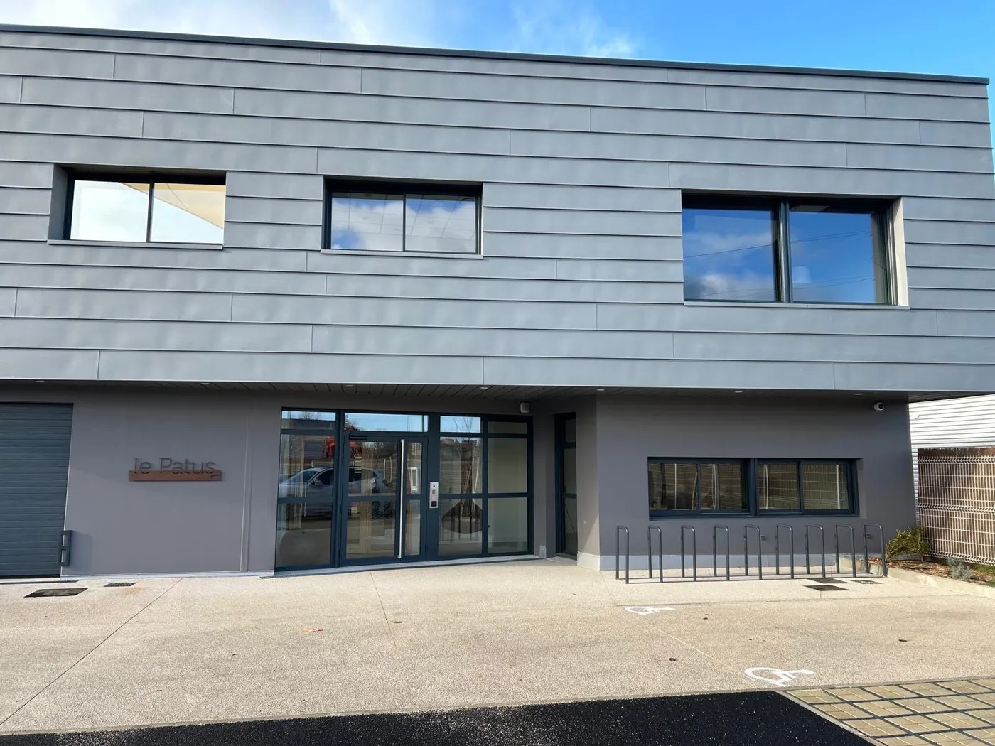 Bâtiment tertiaire Le Patus : fenêtres en bandeau et ensemble d'entrée en aluminium anthracite