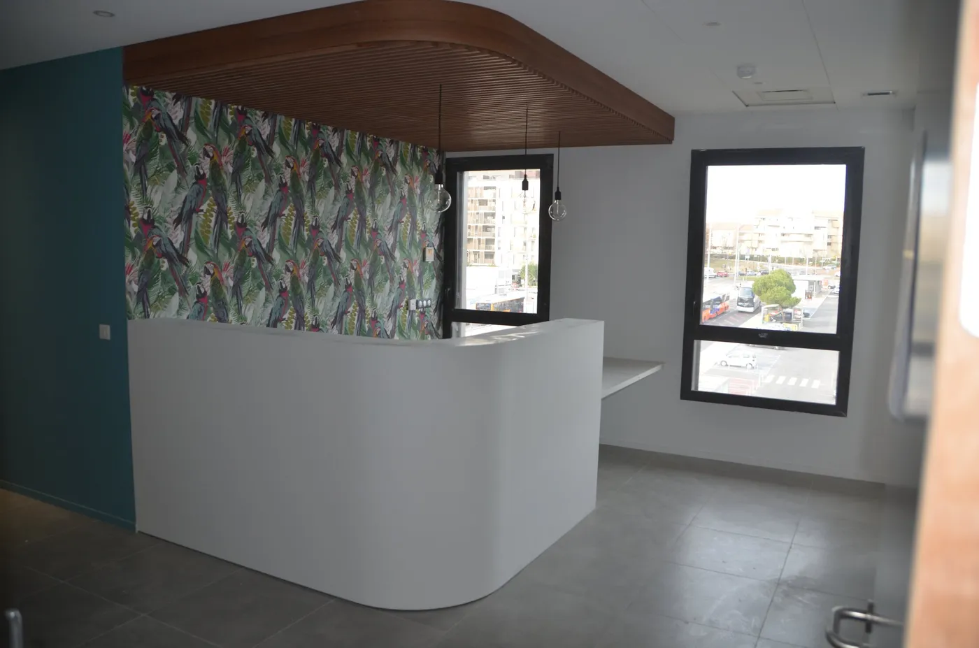 Banque d'accueil courbe blanche sous un plafond à lamelles bois, cabinet médical à Montpellier