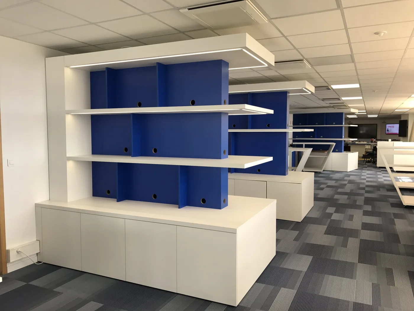 Meuble bibliothèque bleu et blanc au centre d'un plateau de bureaux à Montpellier