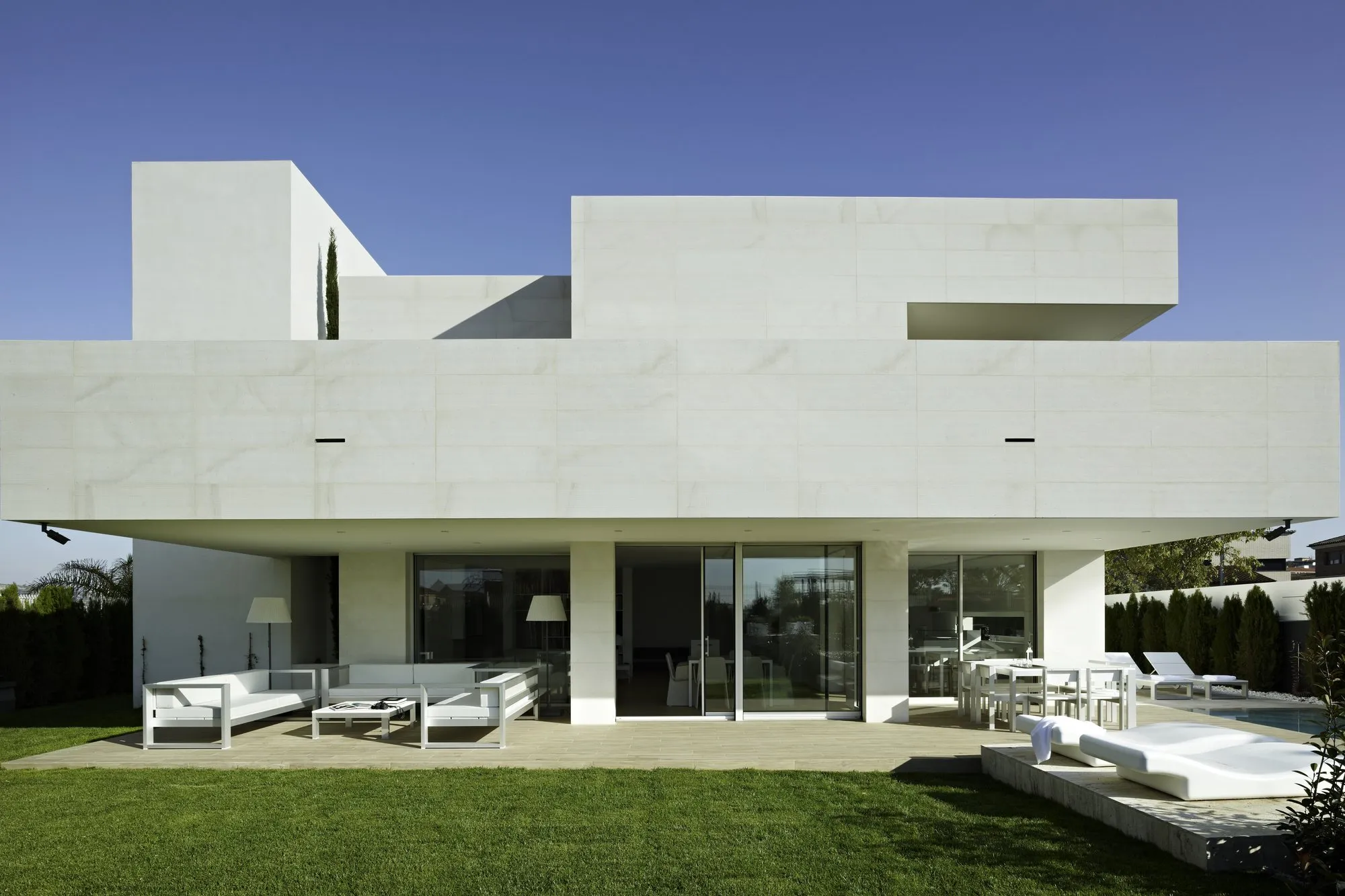 Maison contemporaine blanche ouverte sur le jardin par de grandes baies coulissantes