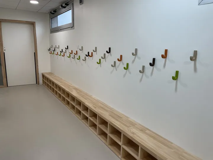 Banc-vestiaire à casiers et patères colorées dans le couloir d'une école