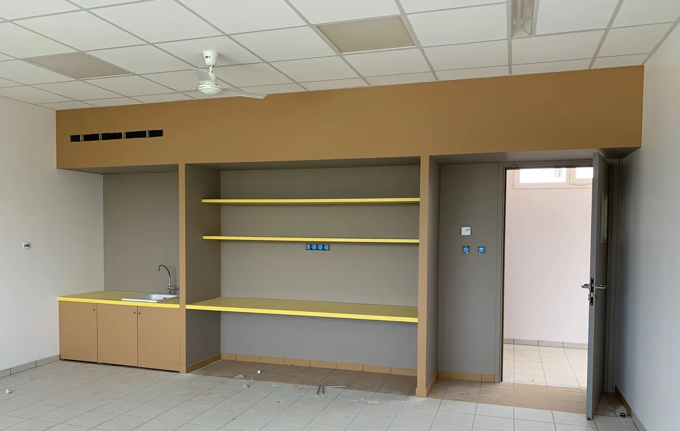 Kitchenette et rangements en bois avec tablettes jaunes dans une école