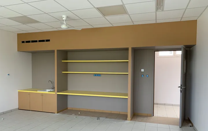 Kitchenette et rangements en bois avec tablettes jaunes dans une école