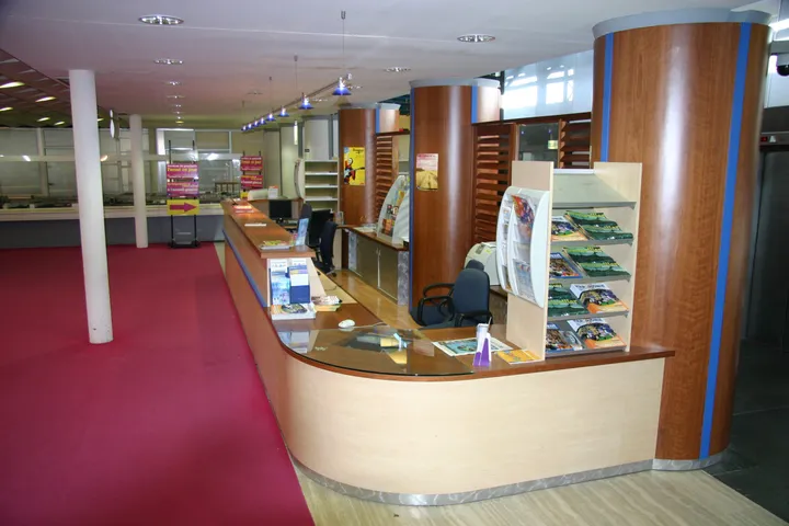 Banque d'accueil courbe en bois clair et colonnes habillées de bois dans un hall de mairie