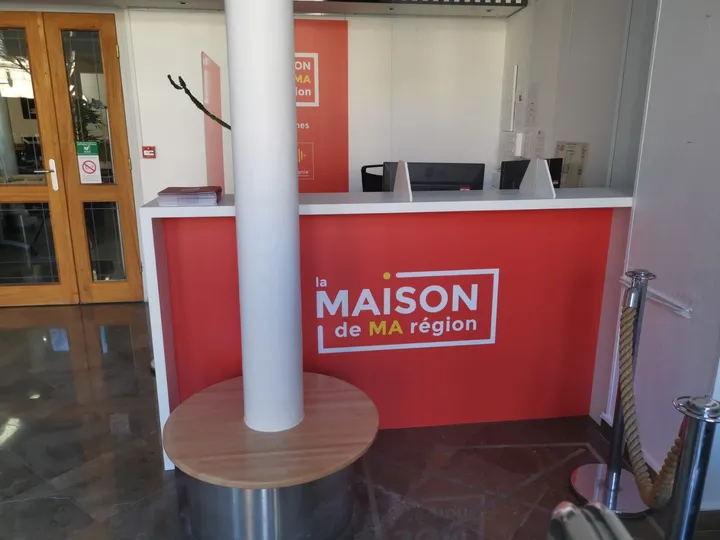 Banque d'accueil rouge et blanche de la Maison de Ma Région à Nîmes