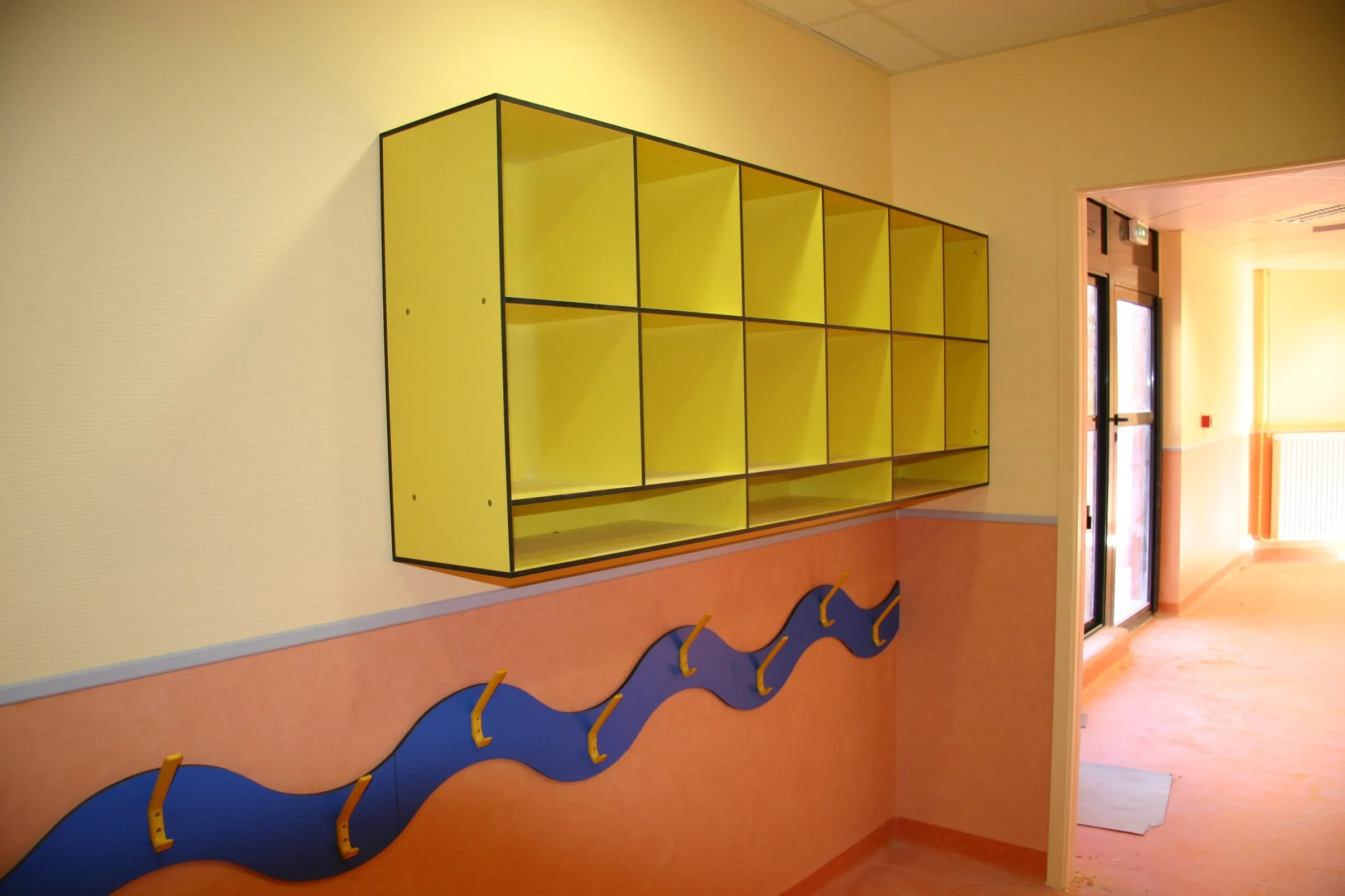 Casier mural jaune et frise bleue ondulée en bas de mur