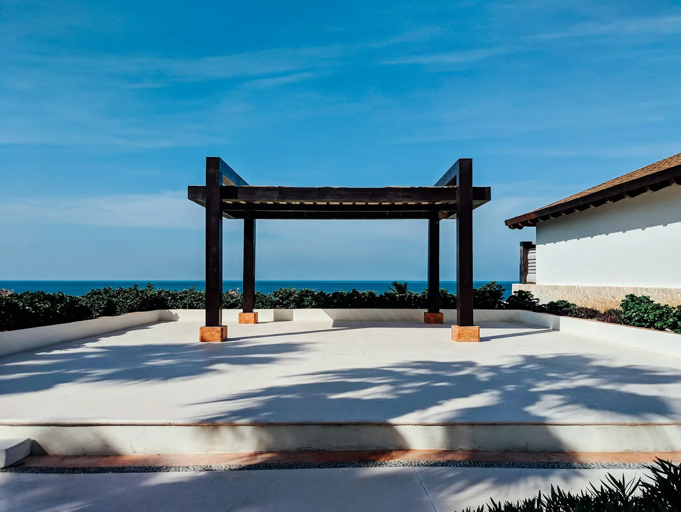Pergola à structure sombre sur une terrasse en bord de mer