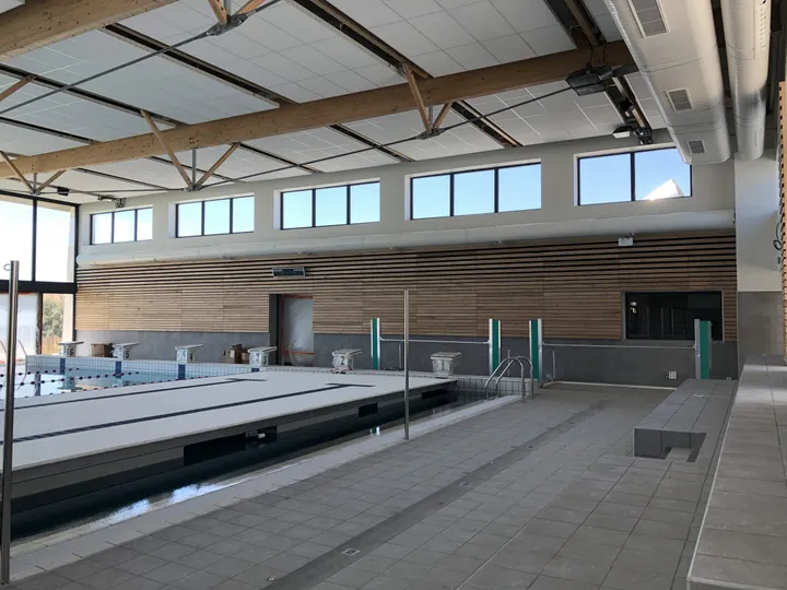 Hall du bassin, mur habillé de bois sous une charpente en lamellé-collé