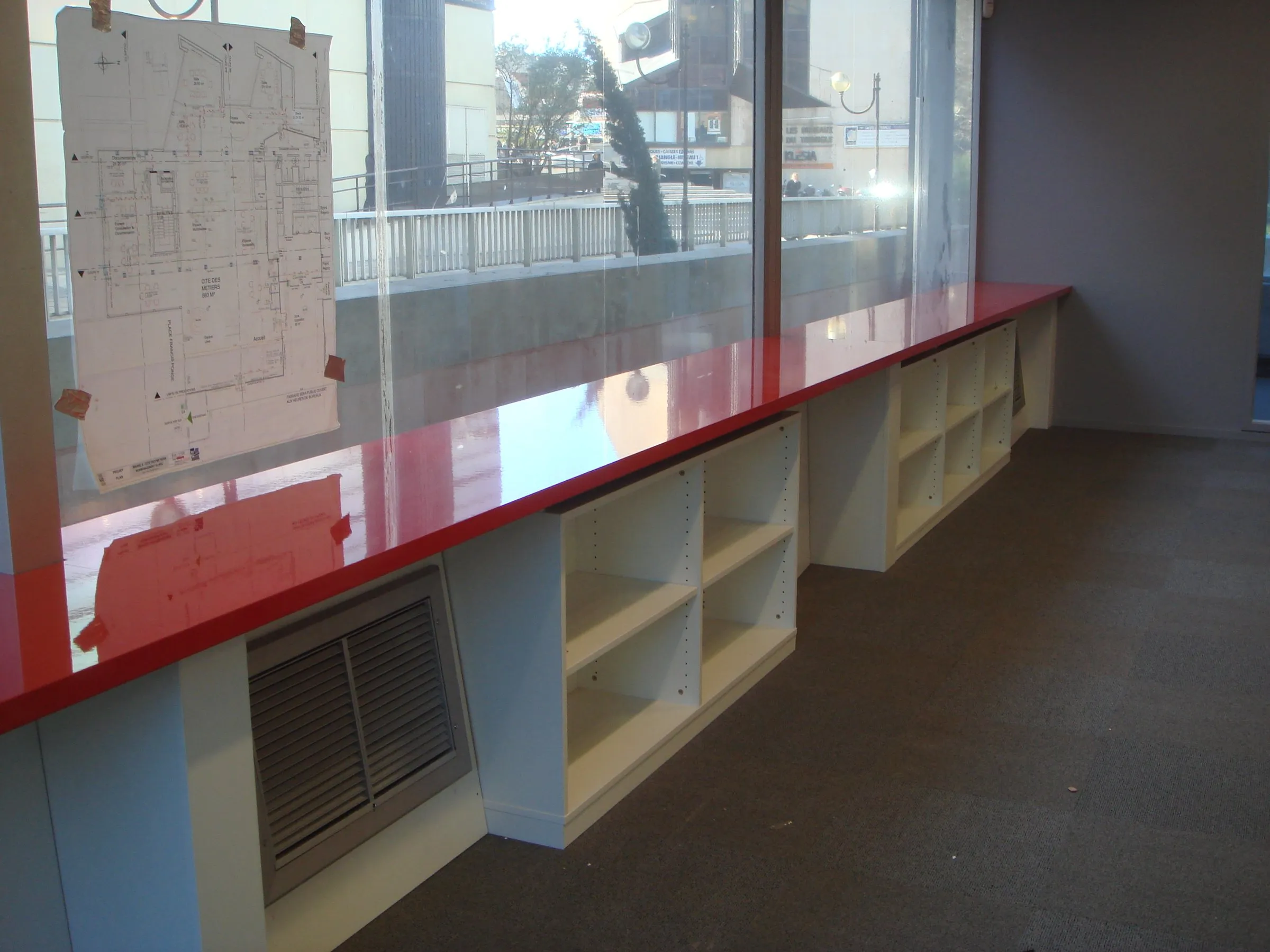 Plan de travail rouge filant le long des baies, rangements dessous