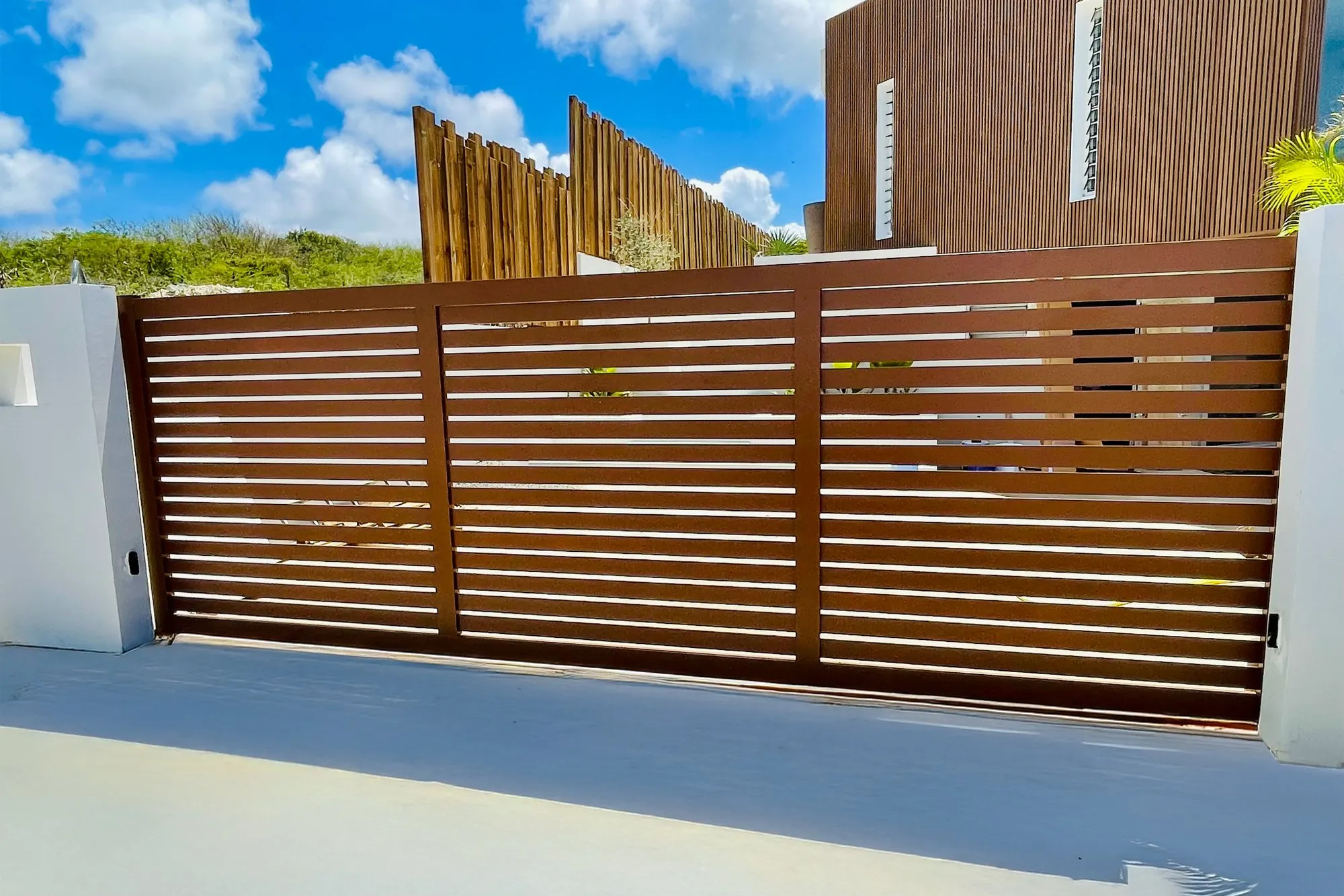 Portail coulissant aluminium à lames horizontales finition bois devant une villa