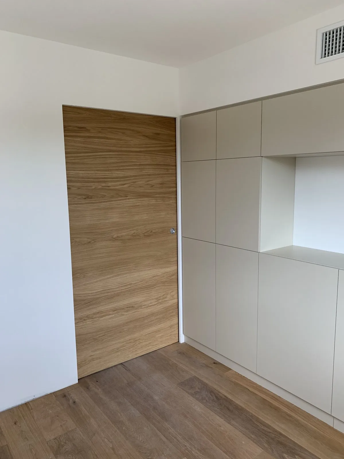 Porte affleurante en chêne intégrée à un mur de rangements sur mesure