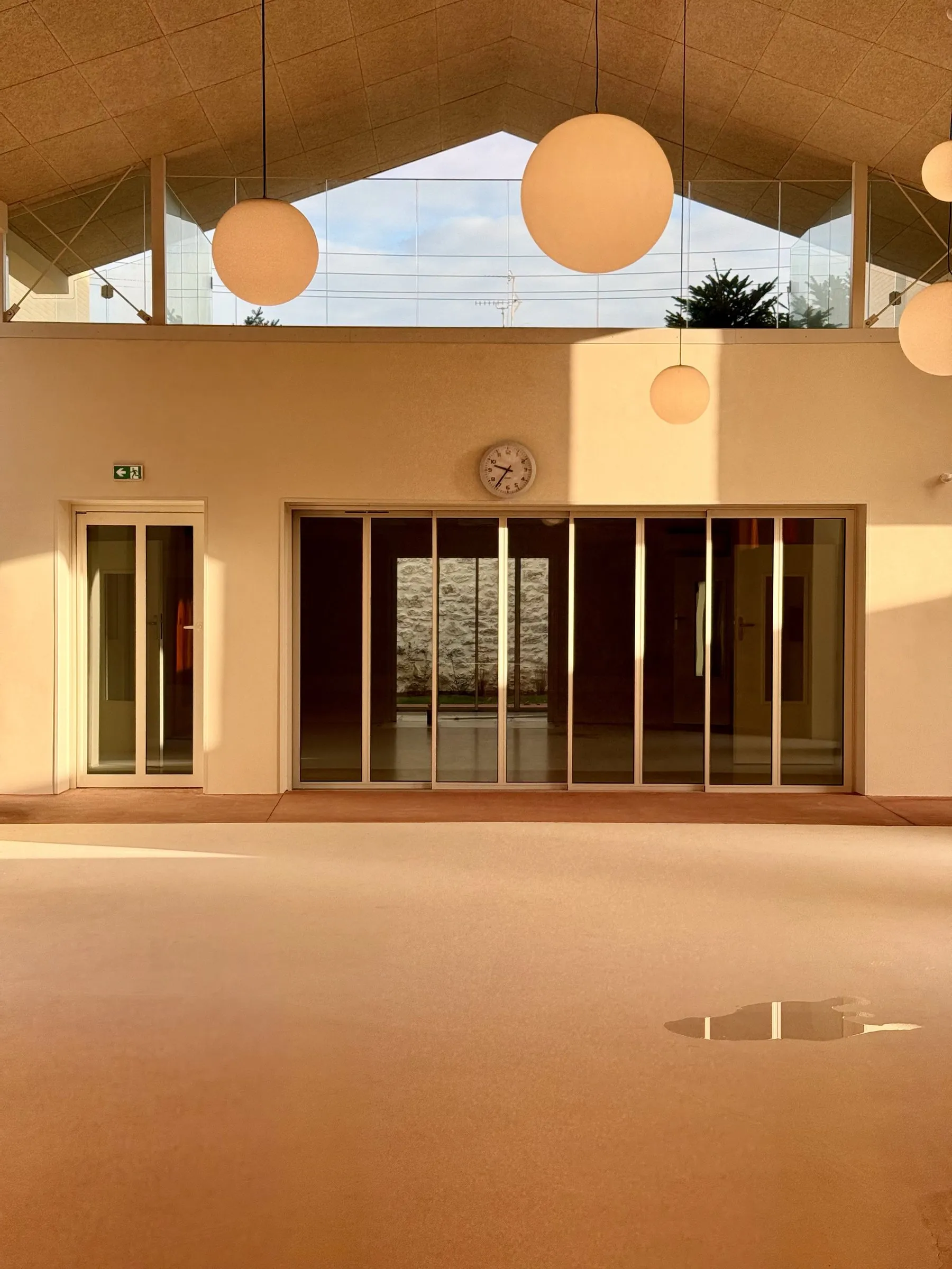 La grande salle : pignon vitré sous charpente et façade de portes coulissantes vitrées