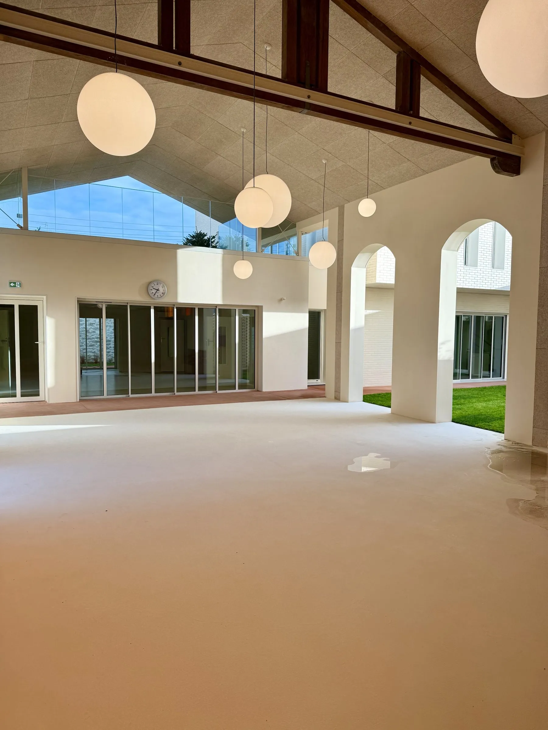 Salle sous charpente apparente, baies en arcade ouvertes sur le jardin
