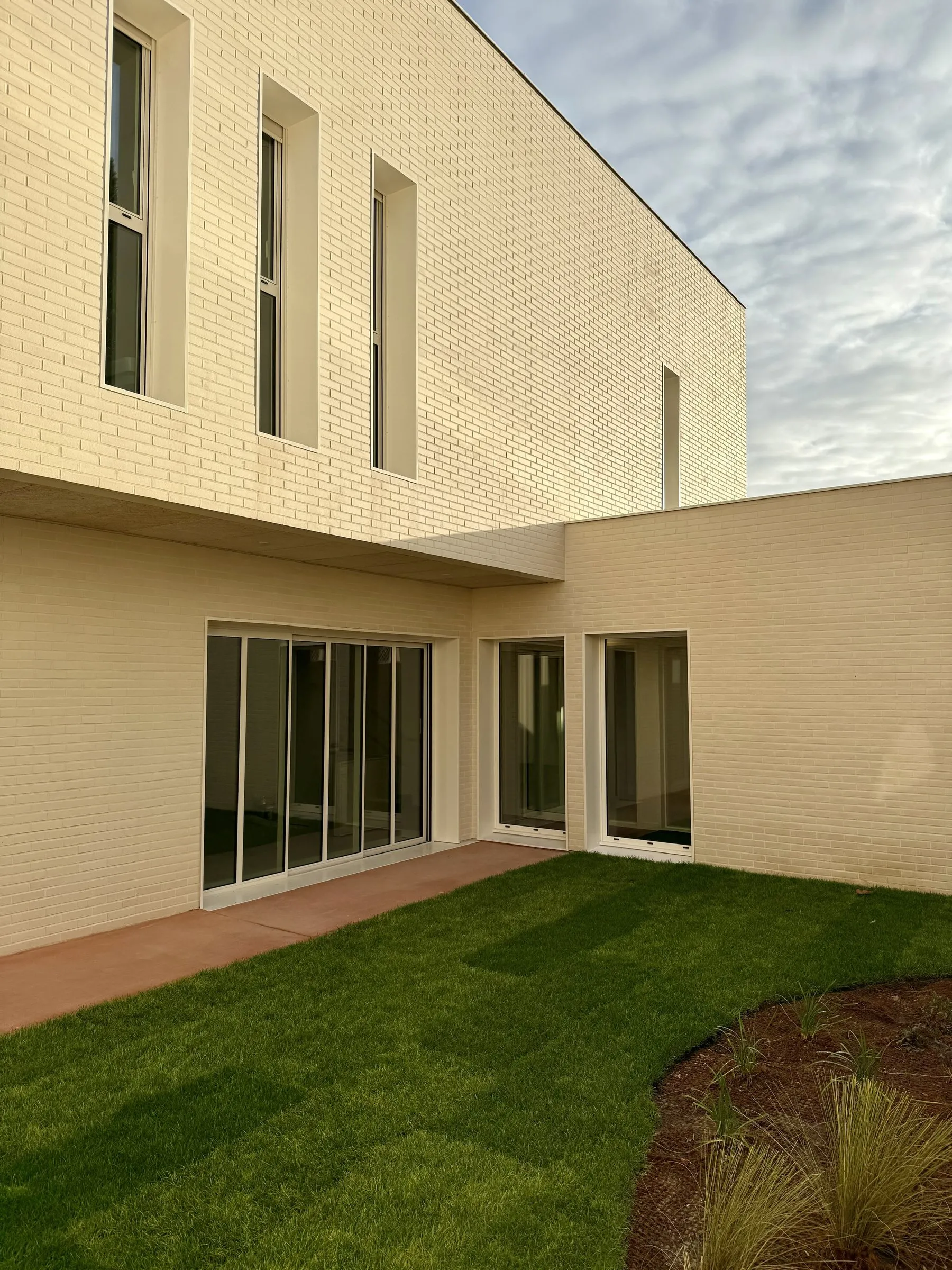 L'extension en briques claires : baies coulissantes et fenêtres hautes sur le jardin