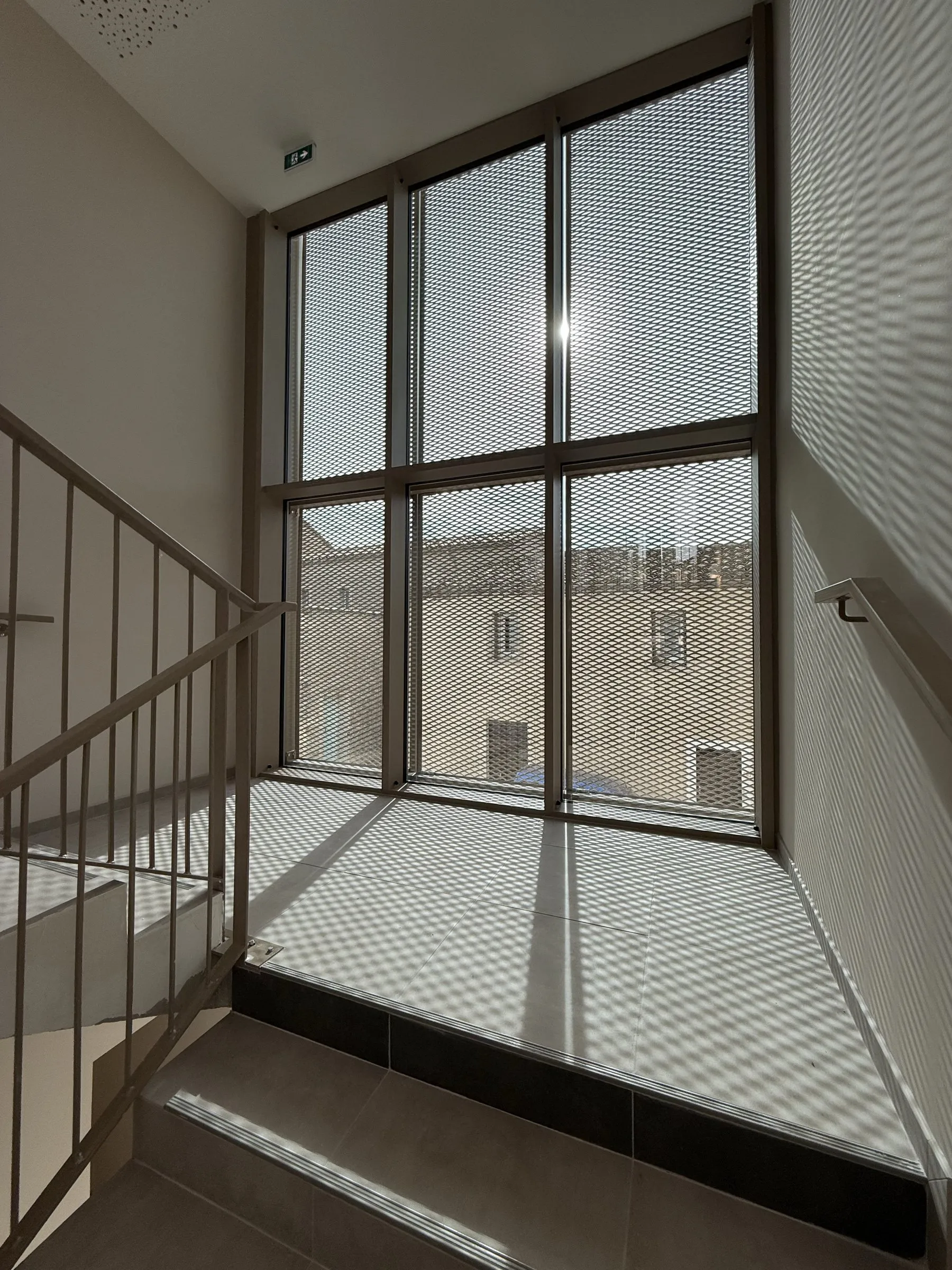 Cage d'escalier : châssis fixe toute hauteur doublé d'une résille métallique