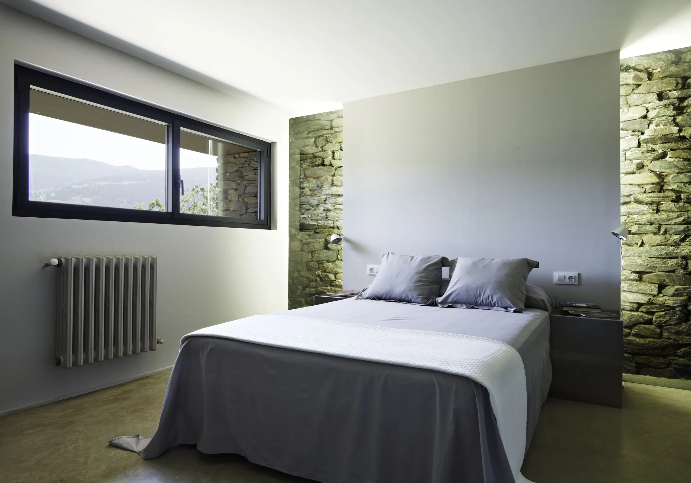 Chambre, fenêtre aluminium en longueur entre deux murs de pierre