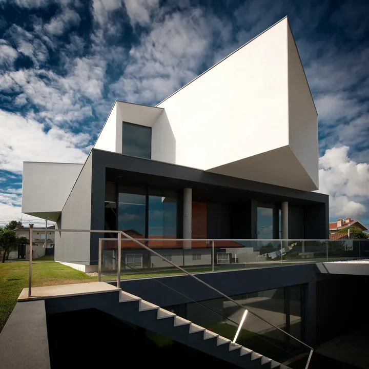 Maison contemporaine en porte-à-faux, baies vitrées aluminium sous le volume blanc