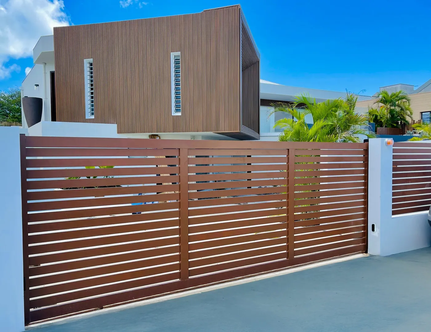 Portail aluminium à lames horizontales ton bois devant une villa contemporaine