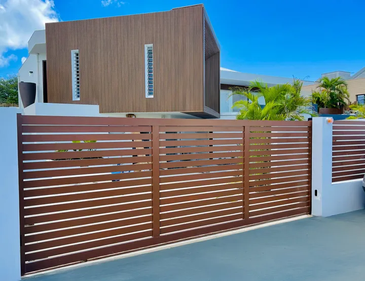 Portail aluminium à lames horizontales ton bois devant une villa contemporaine
