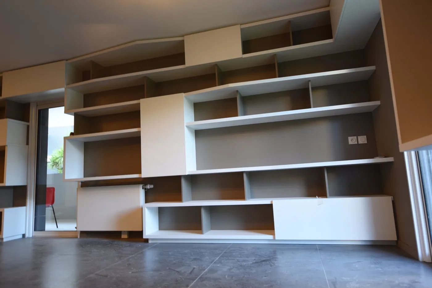Grand mur de bibliothèques asymétriques et rangements sur mesure dans le séjour d'une villa