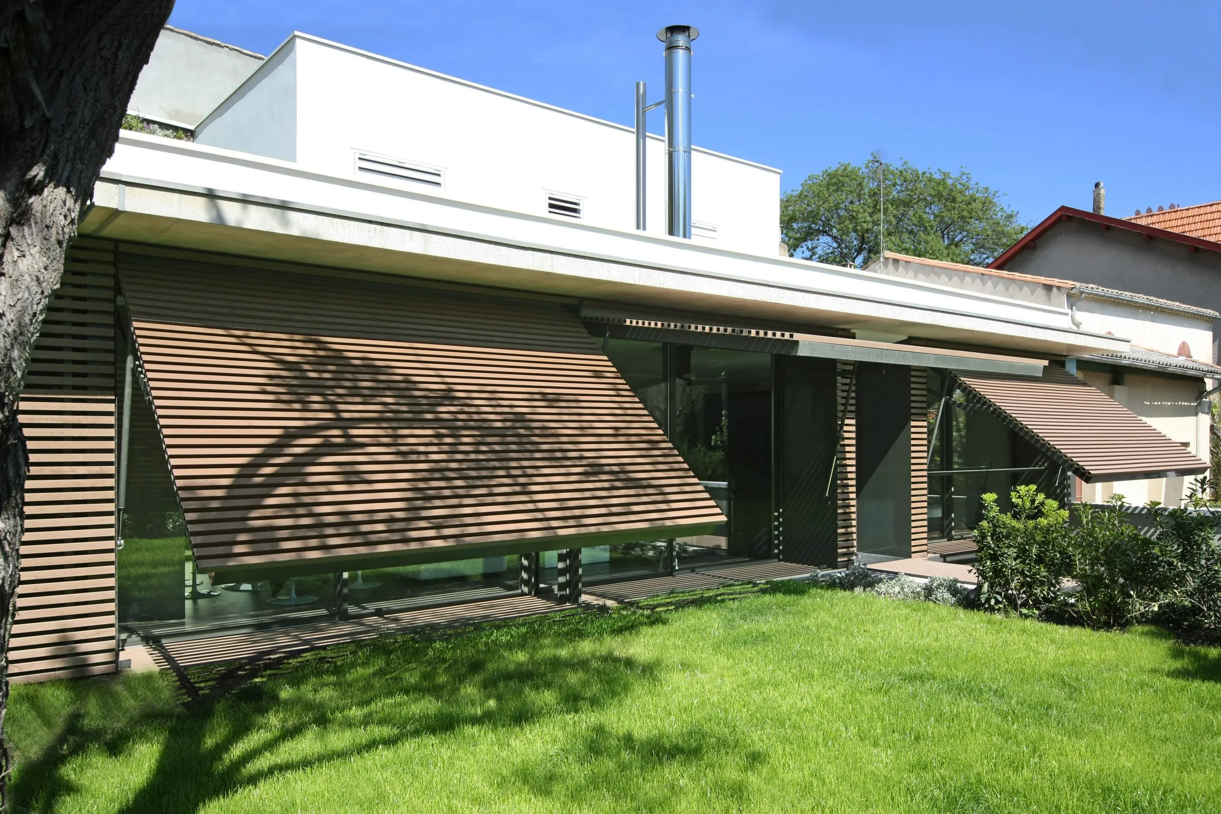 Villa contemporaine à Montpellier, brise-soleil à lames de bois relevés devant les baies vitrées
