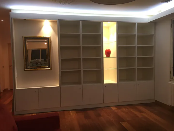 Bibliothèque à niches rétroéclairées dans le salon d'une villa, parquet exotique
