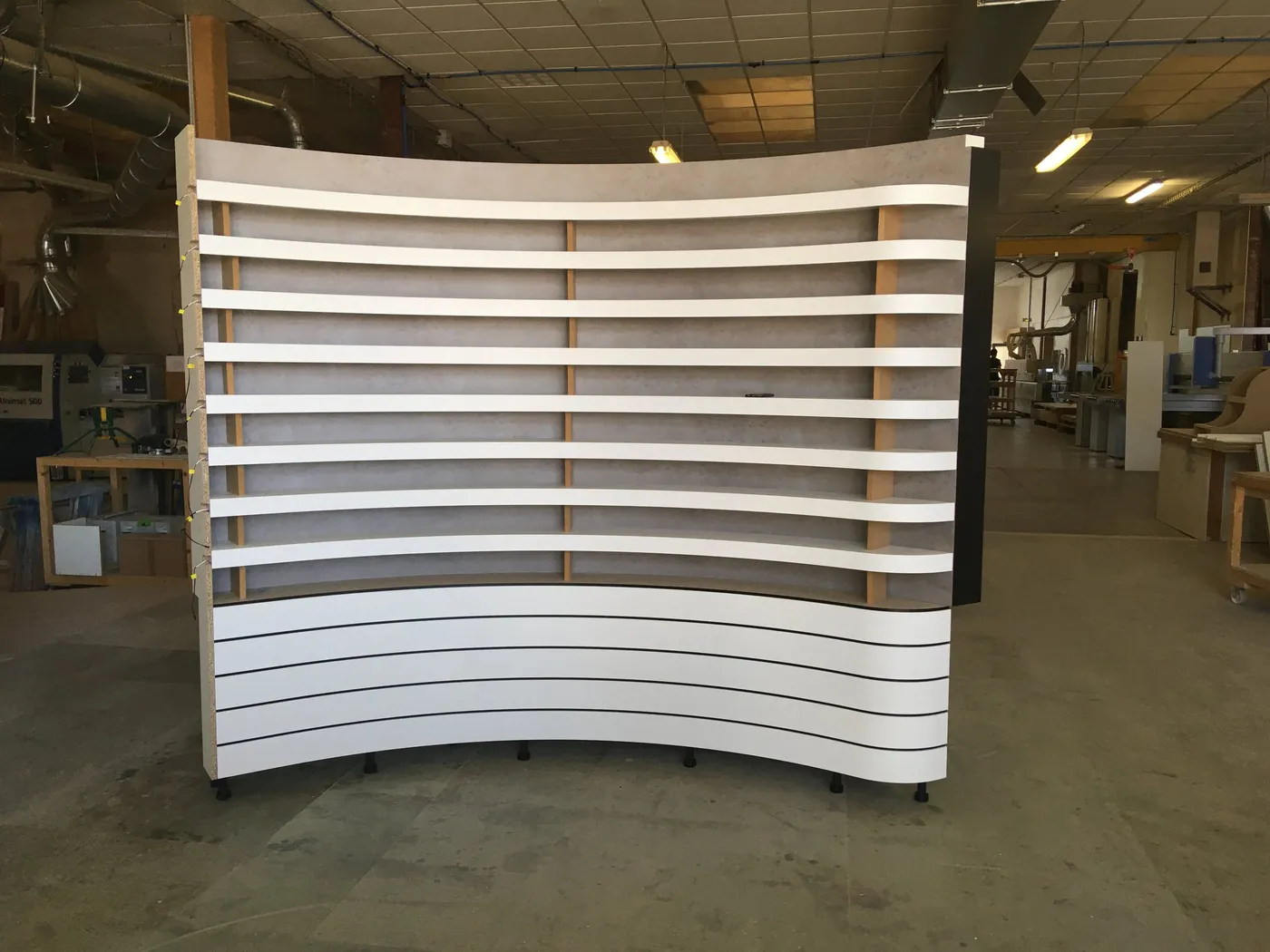 Mur d'étagères à lamelles monté à blanc dans l'atelier avant livraison