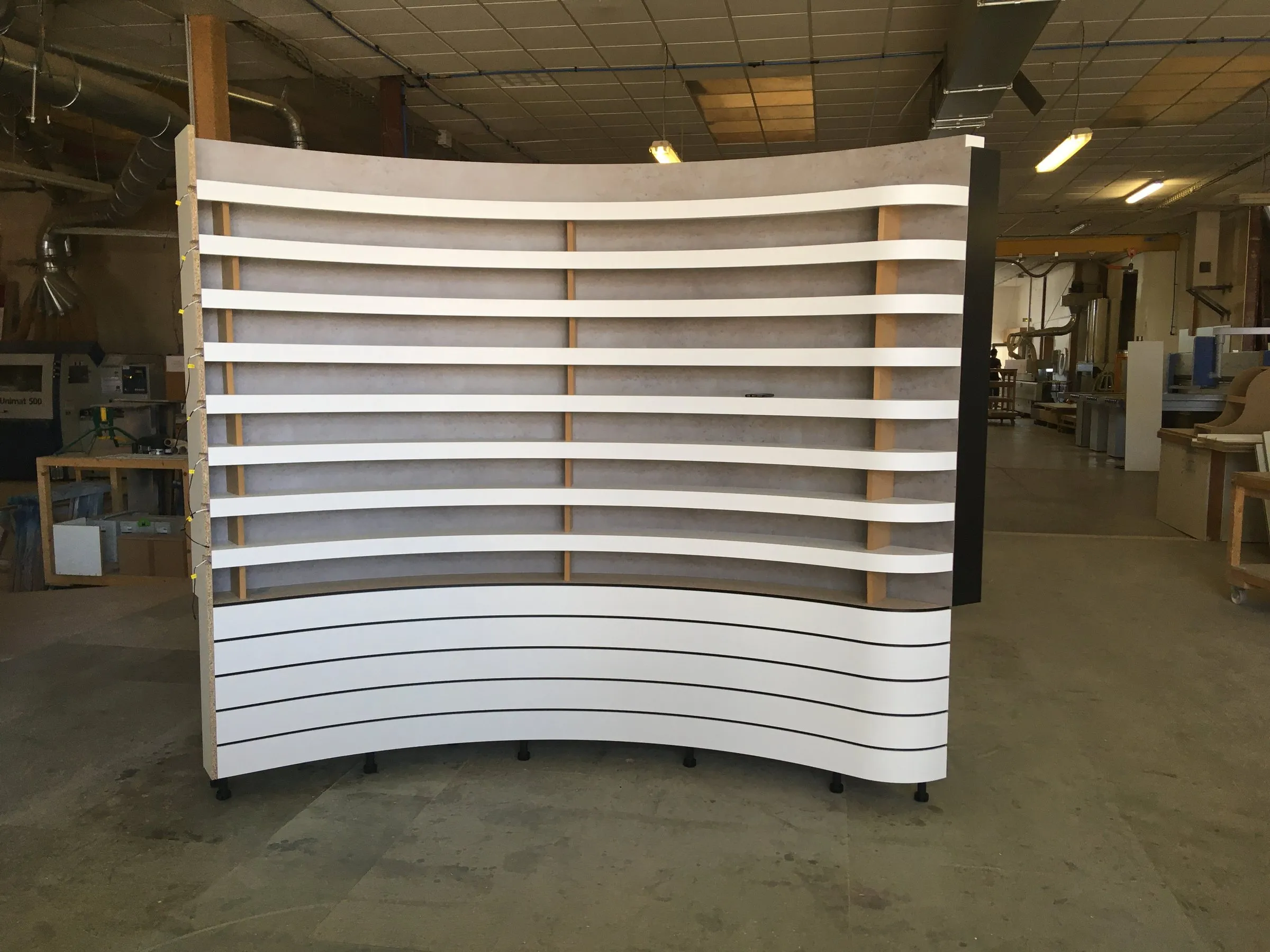 Le mur d'étagères à lamelles monté à blanc dans l'atelier