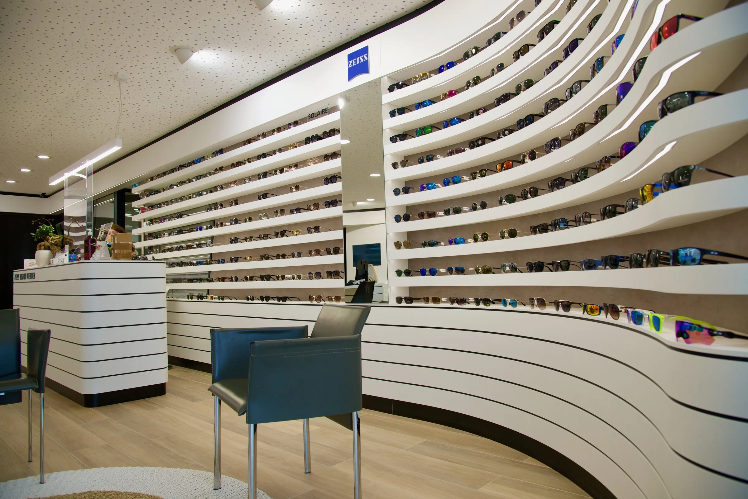 Mur d'étagères cintré à lamelles blanches et comptoir dans un magasin d'optique